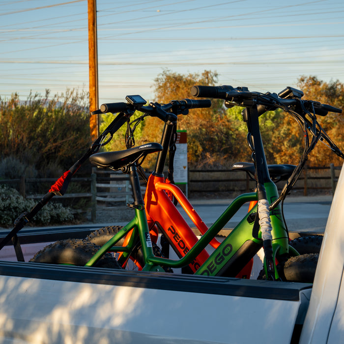 Two Pedego e bikes, strapped down with TorkStraps in the bed of a white pickup truck.