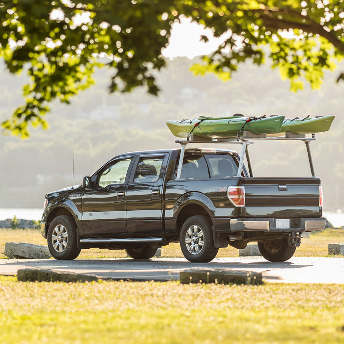Two kayaks fastened down with a set of TorkStraps on the back rack of a pickup truck.