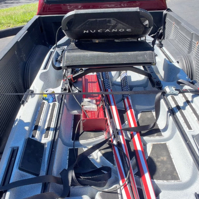Daren positioning a TorkStrap across a fishing kayak in the bed of a red pickup truck.