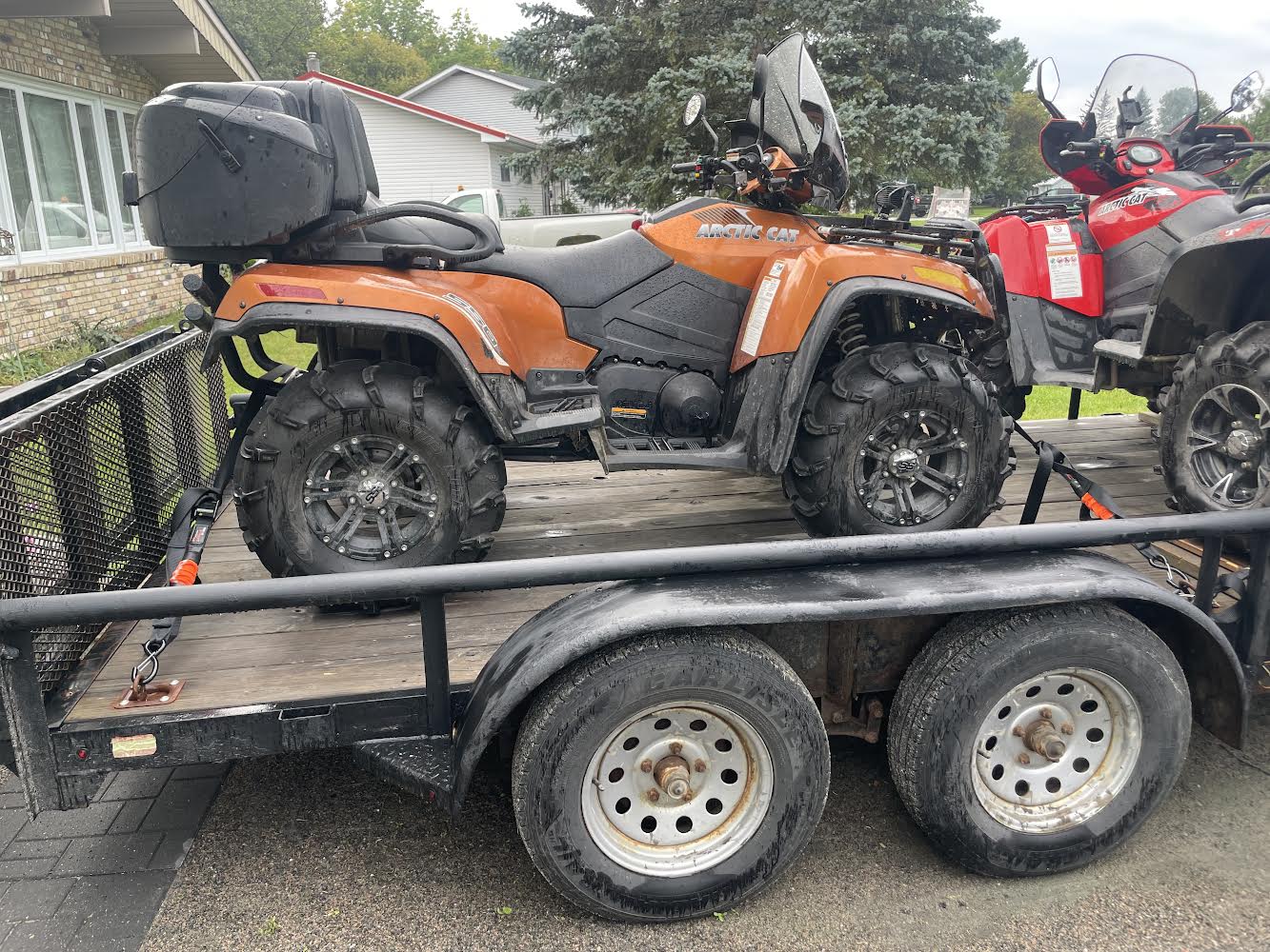 ATV secured on a utility trailer with four ATV tie-down straps attached at the front and rear