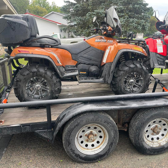 ATV secured on a utility trailer with four ATV tie-down straps attached at the front and rear